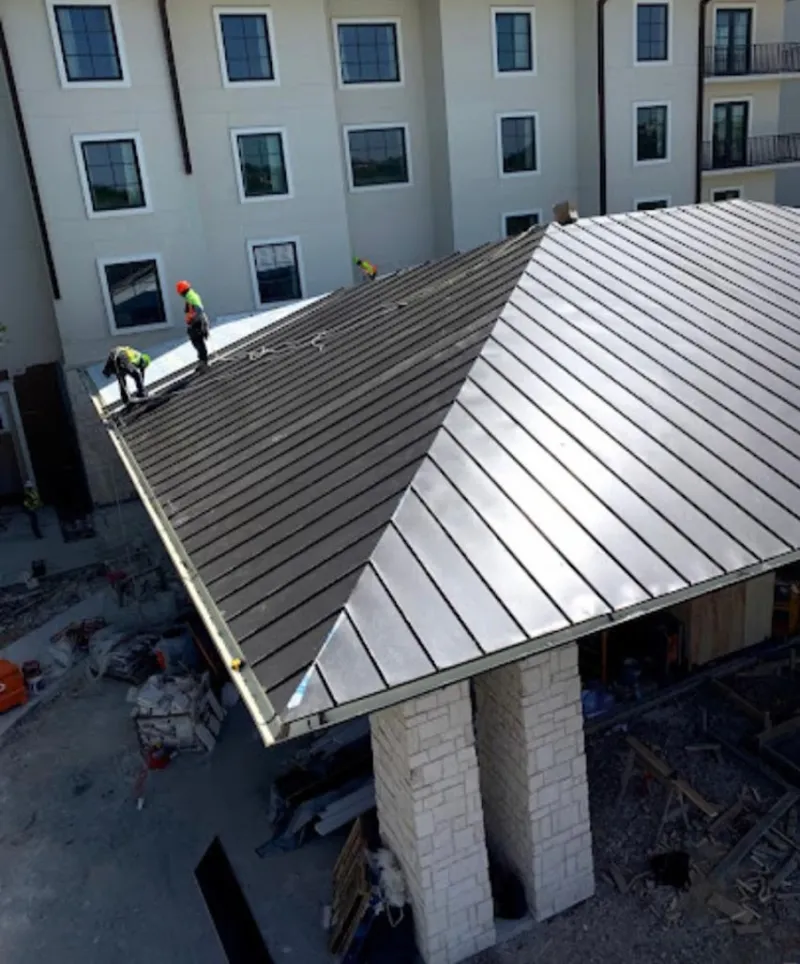 Crew installing standing seam metal roof panels on a commercial project in Oak Lawn